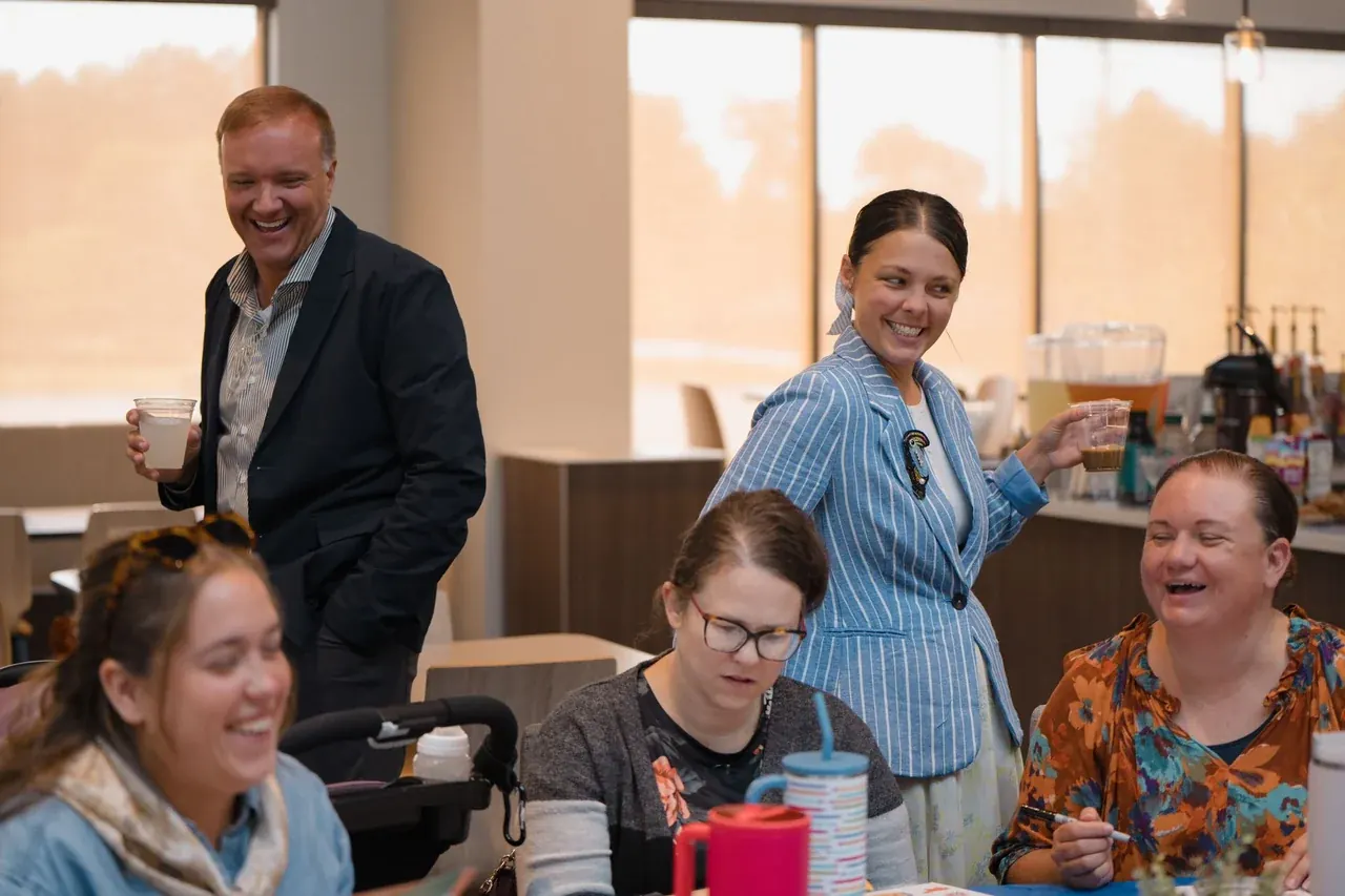 Chad and Fallon with workshop participants around a table, everyone laughing